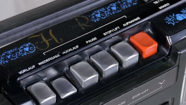 Pushing Button on a Tape Recorder, Play, Stop, Rec, ff, Rew. Close-up. Man finger presses playback control buttons on vintage audio cassette player. Inscriptions in German