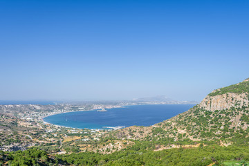 Fototapeta na wymiar Beautiful sunny coast view to the greek mediterranean blue sea after a long hiking day resting at an empty place with some mountains rocks surrounded, Kefalos, Kos, Dodecanese Islands, Greece