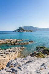 Fototapeta na wymiar Kos Island, Kastri, Dodecanese, Greece: Beautiful sunny coast view to greek mediterranean blue sea with crystal clear water at ancient traditional place or old temple church area near a small islet
