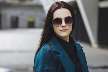 Beautiful brunette girl. Fashionable, stylish with black hair, in coats, jeans and sunglasses