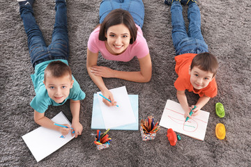 Two little boys drawing with nanny at home