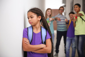 Sad African American girl indoors. Bullying in school