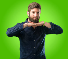 Young hipster man with big beard happy and surprised cheering expressing wow gesture over green background
