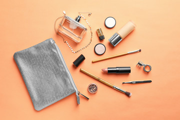 Makeup products with cosmetic bag on color background