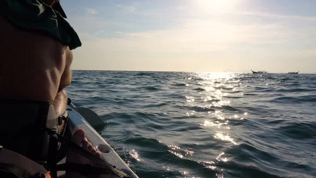 Back View of Strong Man on Kayak in the Open Sea Water. Sunset over the Rock Cliffs. Railey Beach, Krabi, Thailand.