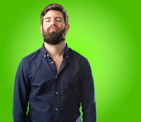 Fototapeta premium Young hipster man with big beard with sleepy expression, being overworked and tired over green background