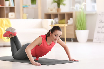 Beautiful young woman doing fitness exercise at home