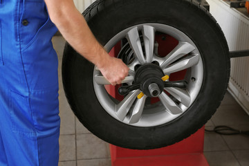 Mechanic balancing wheel in service center. Seasonal tire change