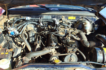 The car's engine is under the open hood. The car's engine is on gas. Close-up. Background.