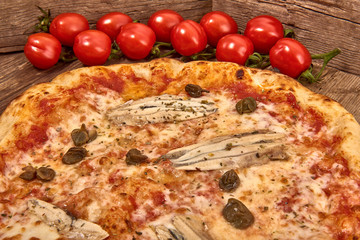 Homemade fresh delicious gourmet pizza Romana whit anchovies,capers and oregano,Tasty italian pizza isolated on wooden table, close up