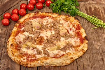Homemade fresh delicious gourmet pizza whit garlic, tuna and artichokes,Tasty italian pizza isolated on wooden table, close up
