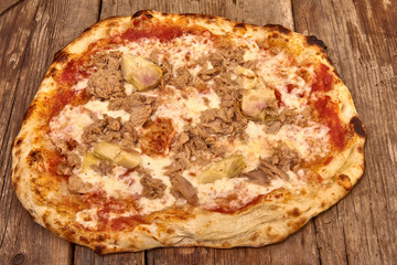 Homemade fresh delicious gourmet pizza whit garlic, tuna and artichokes,Tasty italian pizza isolated on wooden table, close up