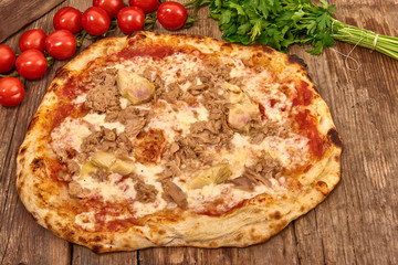 Homemade fresh delicious gourmet pizza whit garlic, tuna and artichokes,Tasty italian pizza isolated on wooden table, close up