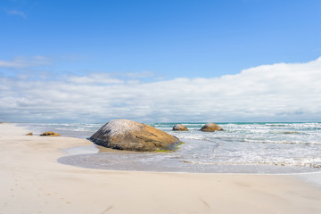 Beautiful sunny coast view to the australian blue sea with waves water and sandy beach at an empty place surrounded by rocks hills granite boulders at shore, Cape Jaffa, Great Ocean, South Australia,