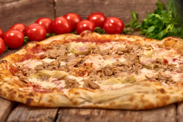 Homemade fresh delicious gourmet pizza whit garlic, tuna and artichokes,Tasty italian pizza isolated on wooden table,Close up with selective focus