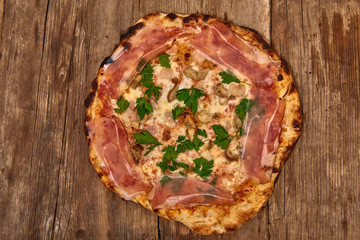 Homemade fresh delicious gourmet pizza whit shrimps, porcini mushrooms, speck, garlic and fresh parsley,Tasty italian pizza isolated on wooden table,Close up with selective focus
