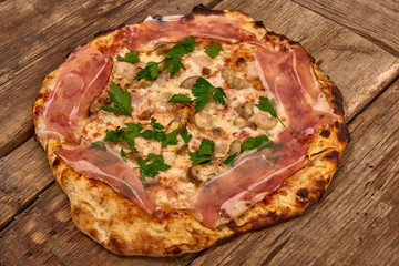 Homemade fresh delicious gourmet pizza whit shrimps, porcini mushrooms, speck, garlic and fresh parsley,Tasty italian pizza isolated on wooden table,Close up with selective focus