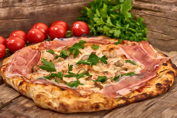 Homemade fresh delicious gourmet pizza whit shrimps, porcini mushrooms, speck, garlic and fresh parsley,Tasty italian pizza isolated on wooden table,Close up with selective focus