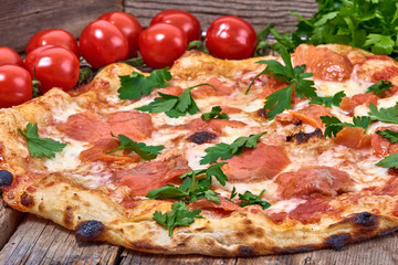 Homemade fresh delicious gourmet pizza whit salmon, garlic and fresh parsley,Tasty italian pizza isolated on wooden table,Close up with selective focus