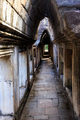 Fototapeta na wymiar Light shines through holes in stone archway over long stone hallway