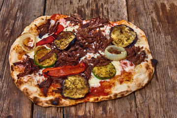 Homemade fresh delicious gourmet pizza whit calf meat and grilled vegetables,Tasty italian pizza isolated on wooden table,Close up with selective focus