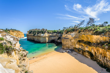Fototapeta na wymiar Bright sunny summer coast view to a beautiful sandy beach bay and rocky erosion sand limestone cliff of Great Ocean Road, walking at Loch Ard Gorge, Port Campbell National Park, Victoria/ Australia