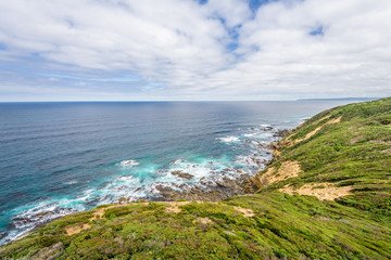 Relaxing at the blue Bass Strait sea and enjoying a warm sunny beach view over blue sky water of Great Ocean Road with a few clouds horizon over small town Apollo Bay, Melbourne, Victoria, Australia