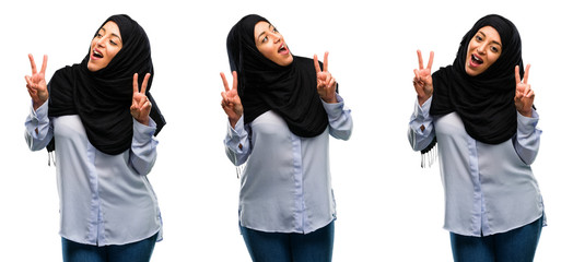 Arab woman wearing hijab happy and excited expressing winning gesture. Successful and celebrating victory, triumphant isolated over white background