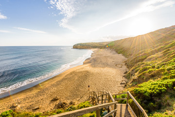 Bright sunny summer sunset sunrise coast view to wild Bass Strait sea, stairs lead you to empty...