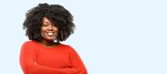 Beautiful african woman with crossed arms confident and happy with a big natural smile laughing, blue background