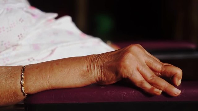 Closeup of paralyzed old woman hands sitting on wheelchair while sunbathing for health on the morning at home