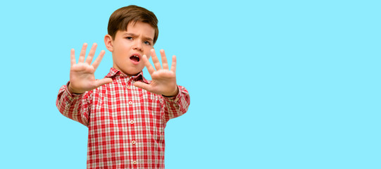 Handsome toddler child with green eyes disgusted and angry, keeping hands in stop gesture, as a...