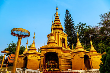 Fototapeta premium Golden light shining on white and gold pagoda during sunrise / sunset with blue sky in Mae hong son Thailand
