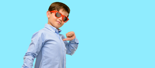 Handsome toddler child with green eyes proud, excited and arrogant, pointing with victory face over blue background