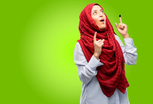 Young Arab Woman Wearing Hijab Happy And Surprised Cheering Expressing Wow Gesture Pointing Up