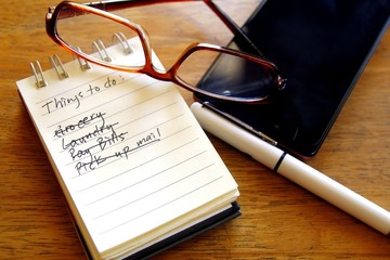 Checklist on a notebook, pen, eyeglasses and smart phone