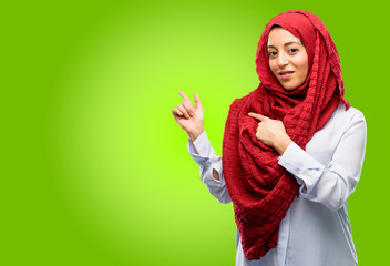 Young arab woman wearing hijab pointing away side with his finger