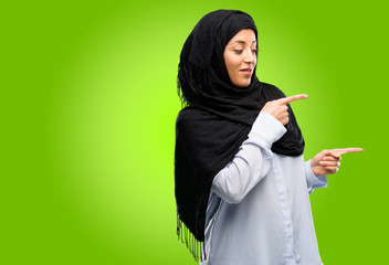 Young arab woman wearing hijab pointing away side with finger