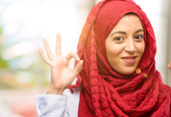 Young arab woman wearing hijab doing ok sign gesture with both hands expressing meditation and relaxation