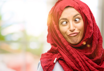 Young arab woman wearing hijab making funny face fooling