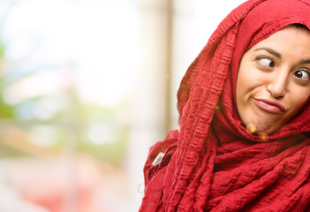 Young arab woman wearing hijab making funny face fooling