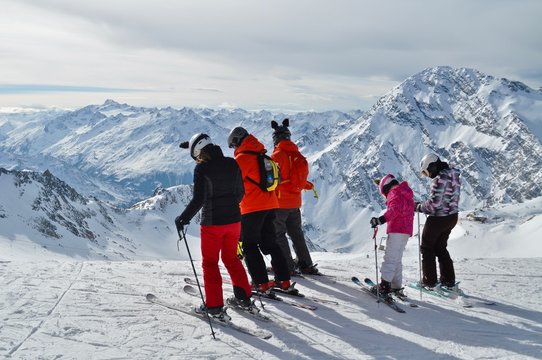 Familie in Skikleidung steht auf Ski, beim Schaufeljoch Panorama des Stubai Gletscher mit Sicht auf die Tiroler Berge