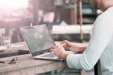 Young male freelancer sitting in cafe working in laptop