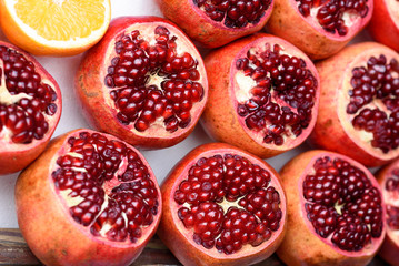 Juicy pomegranates with seed and half fleshy orange. Healthy fruits background.