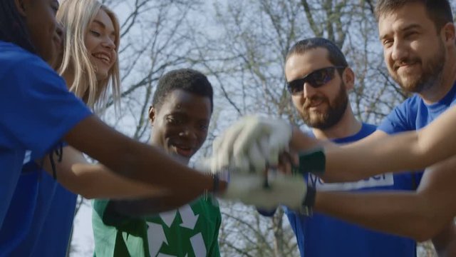 Cheerful diverse men and women in volunteer group talking and stacking hands for inspiration working together.