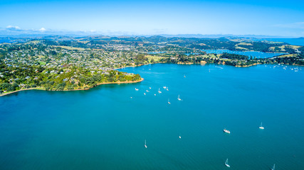 Aerial view on beautiful bay at sunny day with sandy beach and residential houses on the background. Waiheke Island, Auckland, New Zealand