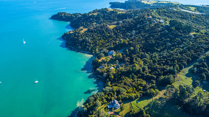Aerial view on beautiful bay at sunny day with sandy beach and residential houses on the background. Waiheke Island, Auckland, New Zealand