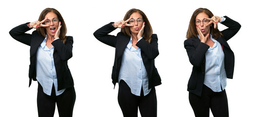 Middle age business woman looking at camera through her fingers in victory gesture winking the eye and blowing a kiss over white background