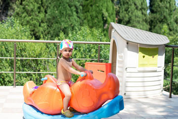 Cute little girl having fun on a playground outdoors in summer.