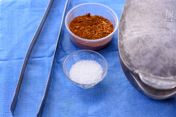 Preparing for a barbecue outside in the Summer Garden. Pots, bbq tongs, salt, spices on a table with a blue tablecloth.Retro style.